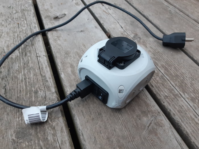 Portabel jordfelsbrytare på träyta med anslutna kablar och skyddslock.