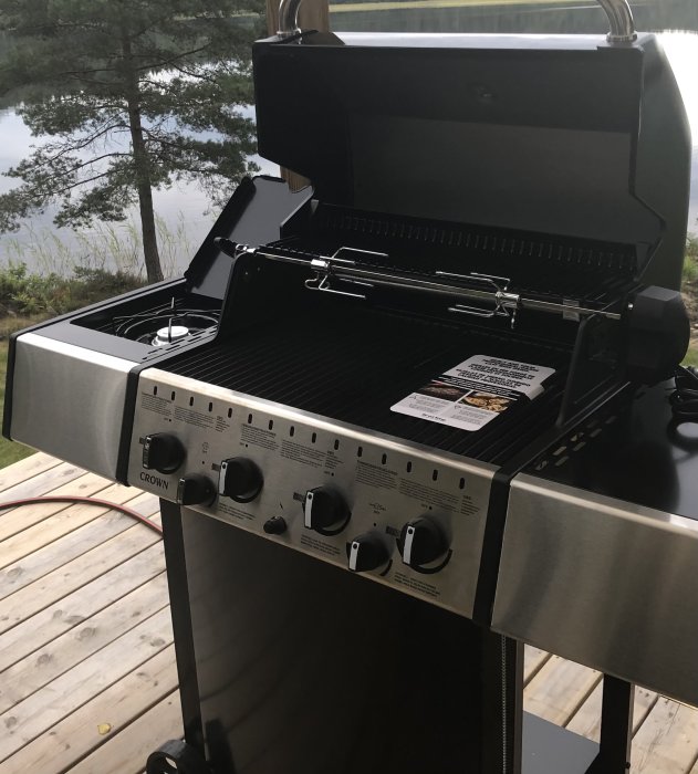 Ny gasolgrill på trall med utsikt över en sjö och träd.