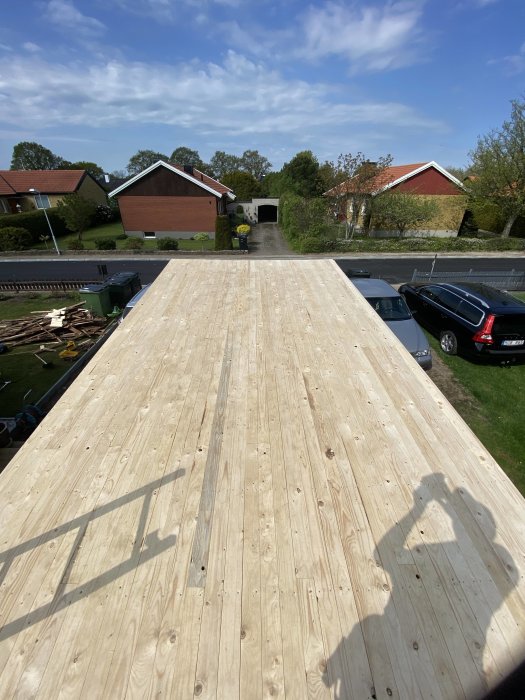 Nytt trägaragetak med skuggor, omgivet av bostadshus och grönska.