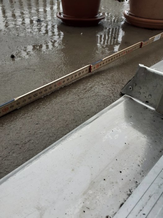Måttbandet visar avståndet mellan balkongdörr och betonggolv med synligt lut på balkongen.