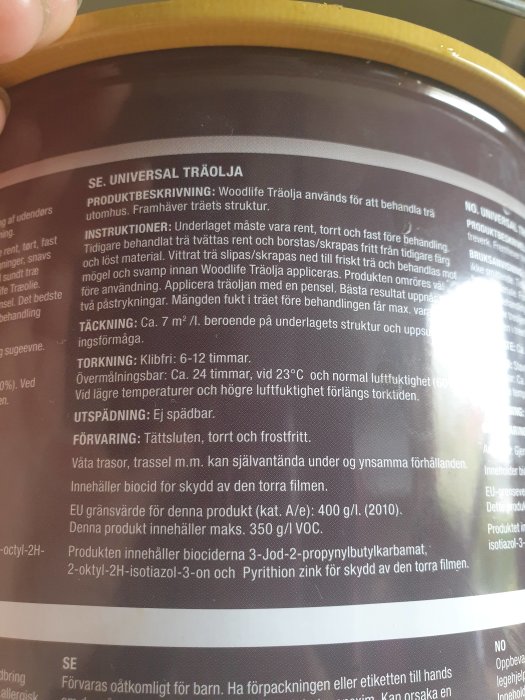 En hink med träolja och en produktbeskrivning som lyder 'Woodlife Träolja', inklusive instruktioner och tekniska detaljer.