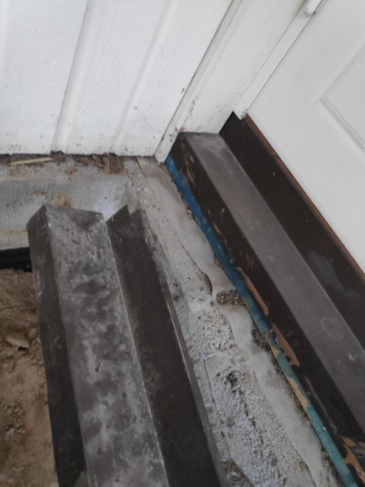 Tröskelområde vid en dörröppning med synlig fuktspärr och ojämna kanter, redo för fogning, under pågående renovering.