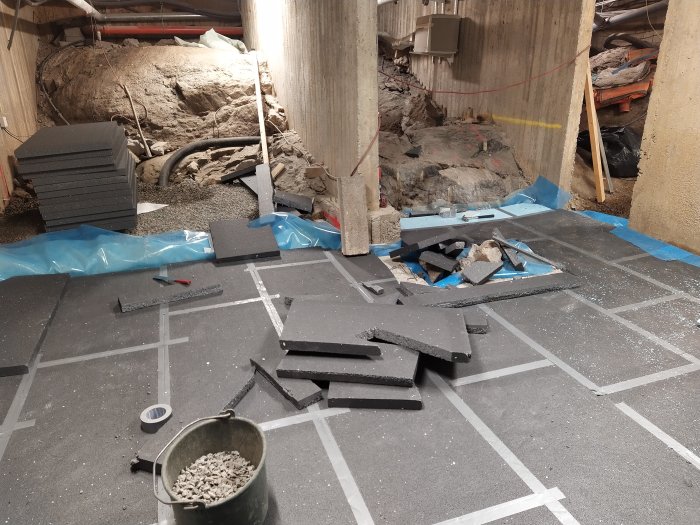 Renoveringsarbete med utjämnat golv, isolermaterial och verktyg i en källare.