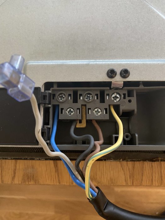 Kabelanslutningar på gammal induktionshäll med blå, brun, svart och gulgrön tråd i Perilex-kontakt.