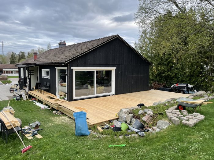 Nybyggd trall framför hus, med verktyg och material för fortsatt byggande.