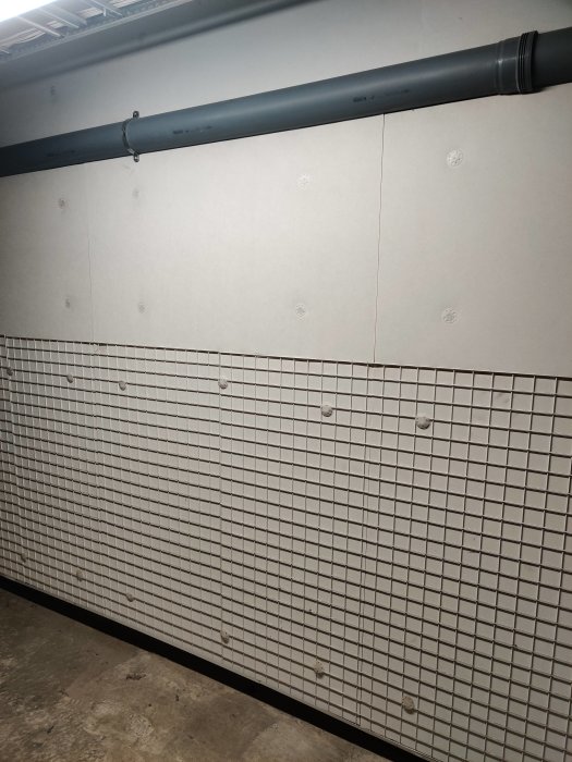 Vit isolering med nätstruktur i ett garage, möjlig mineralull, skadad med genomföring.