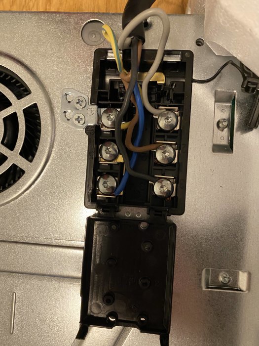 Elektrisk anslutning av en spishäll med gul och blå kabel kopplade i en svart anslutningsdosa.