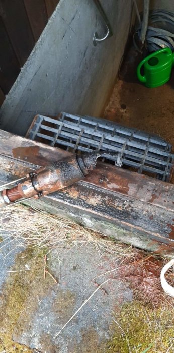 En ejektor från en Grundfos-brunnpump som brutits av och ligger på träplankor.