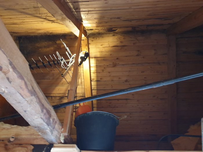 Påbörjat renoveringsprojekt av vind med synliga träbjälkar och isoleringsmaterial.