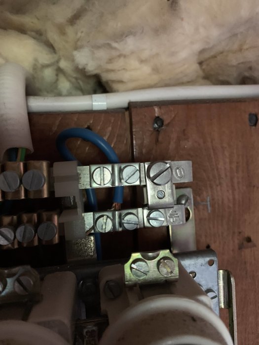 Elektriskt skåp med en blå kabel kopplad till jordfelsbrytare och andra kablar i en fördelningsplint.