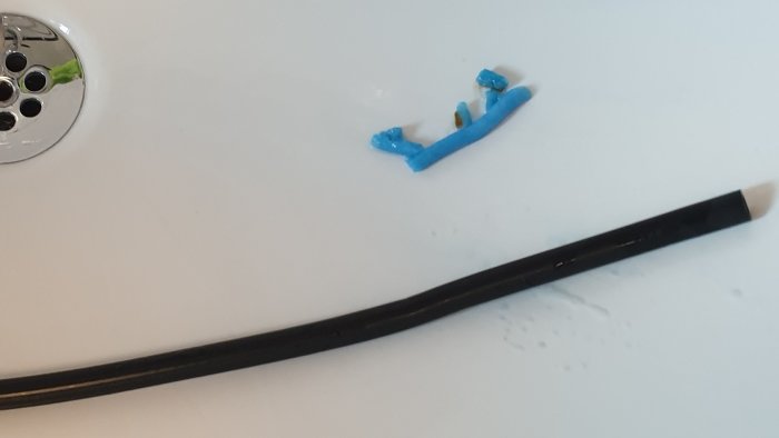 Rengjorda blå tvättmedelsrestbitar och svart slang på vit yta, kopplade till Miele WKG130.