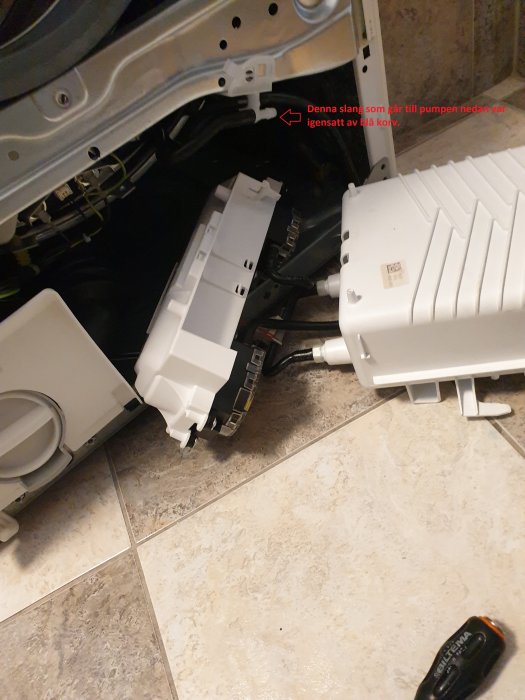 Tvättmaskin öppnad med synlig slang och tvättmedelsbehållare, rengöring utförd på slang.