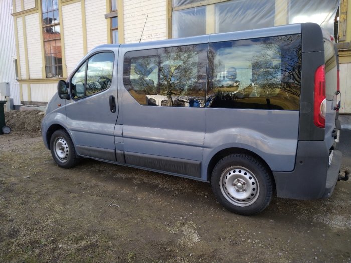Grå arbetsbil parkerad framför byggnad på en byggarbetsplats.