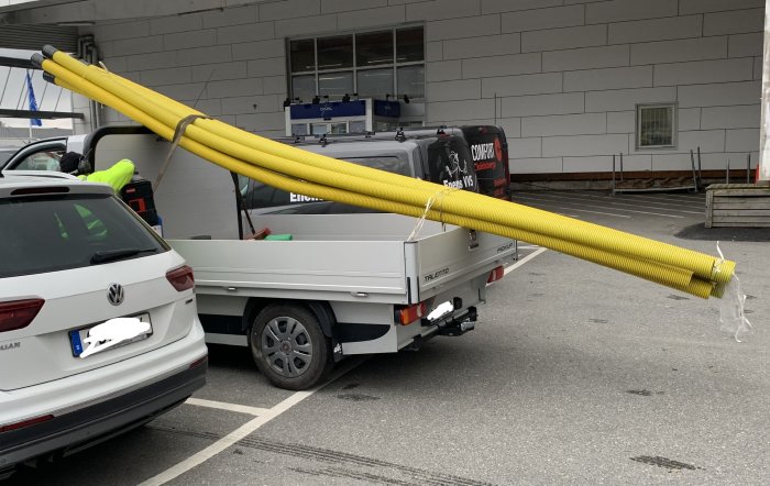 Gula isoleringsrör lastade på släp vid byggvaruhus.