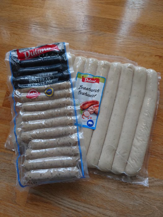 Två förpackningar med tyska Bratwurst-korvar på ett träbord.