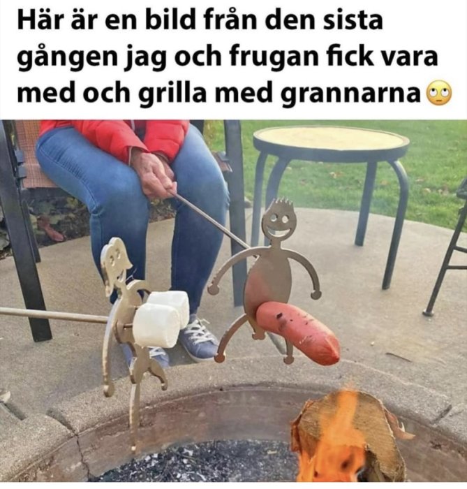 Två personer grillar med roliga metallfigurer över en eldstad, en håller marshmallow och den andra en korv.