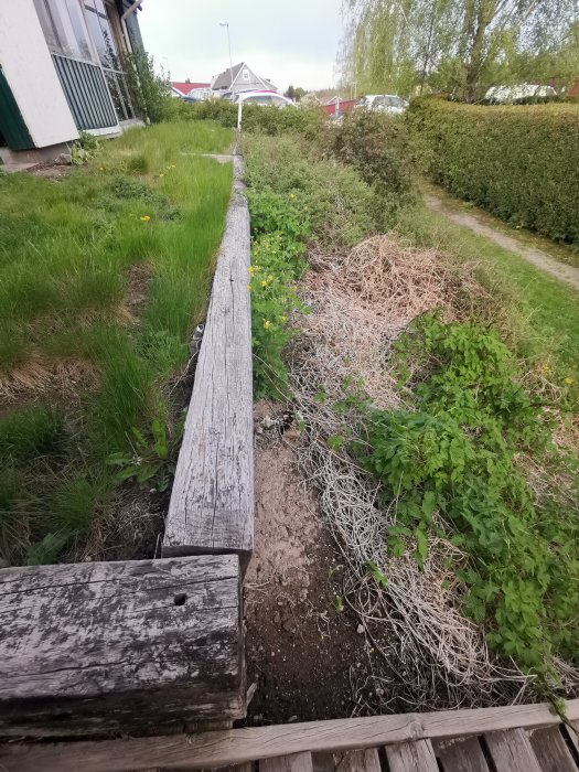 Trädgårdsmark med en äldre träbalk som bärlina och föreslagna plats för inglasat uterum.