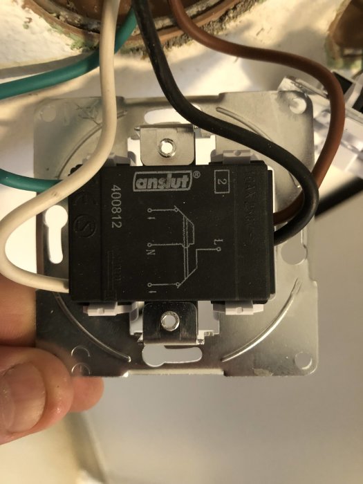 Ny strömbrytare monterad på vägg med synliga elektriska kablar i olika färger och anslutningsschema.