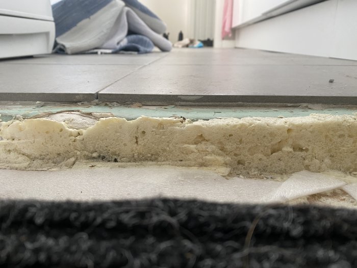 Glipa och nivåskillnad mellan två golvtyper med skumisolering som syns.