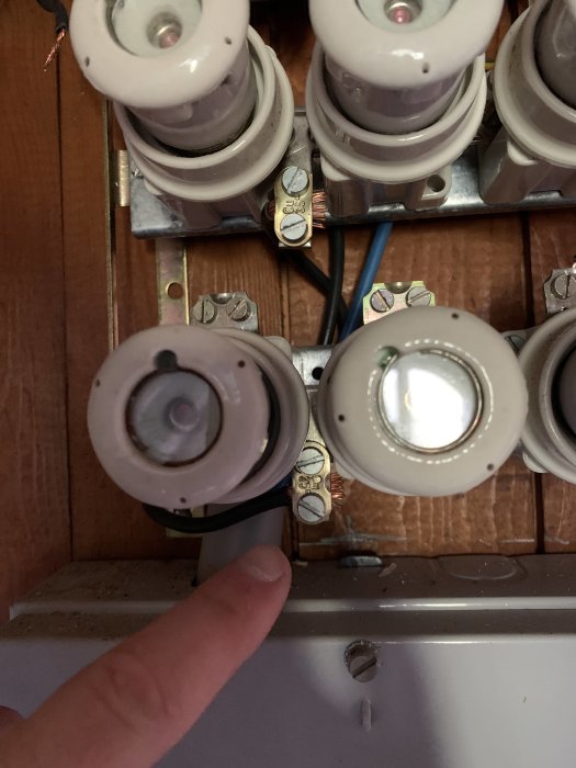 Elcentral med säkringar och en pekande finger som indikerar problem med de övre säkringarna.
