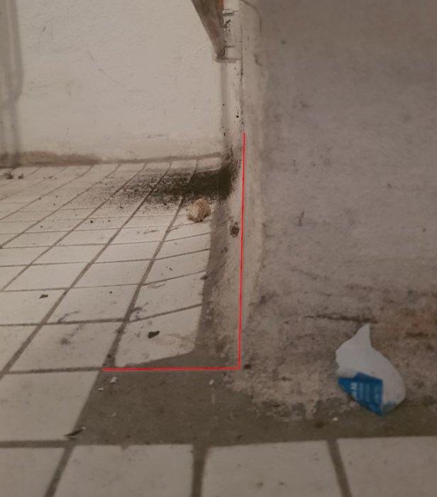 Hörnet av en källartvättstuga med murade väggar, gjutet golv och rundad övergång markerad med röda linjer.