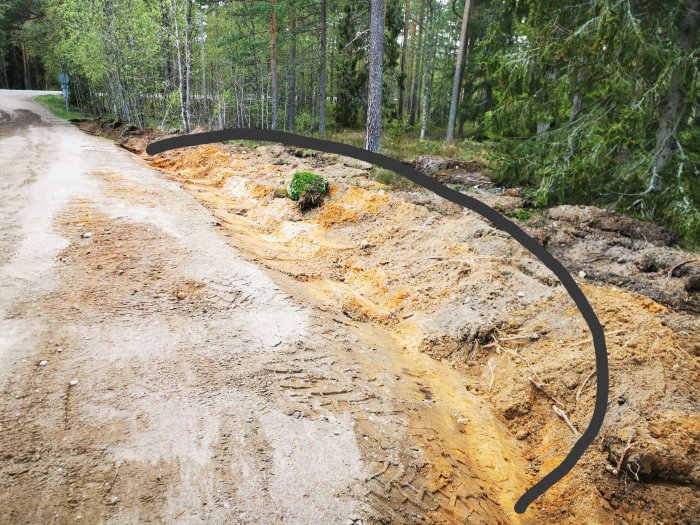 Grusväg med en smalare del och en svart markering där parkeringsfickan tidigare varit.