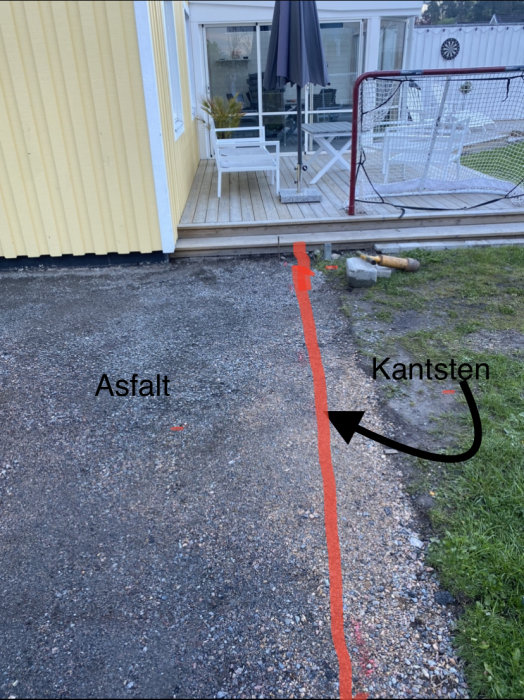 Uppfart med markerad linje för tänkt placering av trädgårdskantsten vid hus och altan.