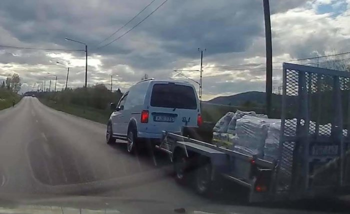 Bil med överlastad släpvagn orsakar lågtryck i trafik på landsväg.