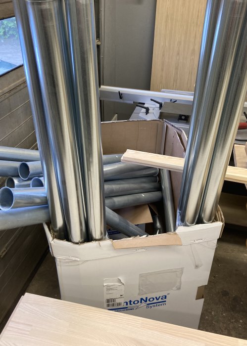 Delar till centraldammsugare inklusive rör och kopplingar i en öppnad kartong.