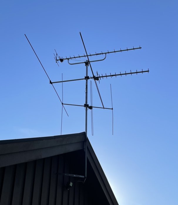 Gamla trasiga TV-antennen monterad på husets tak mot en klarblå himmel.