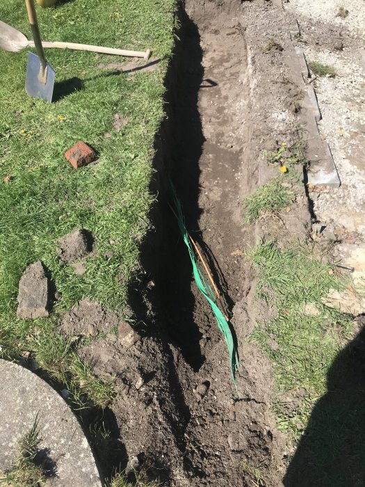 Uppgrävd trädgård med synlig fiberkabel, gammal grund och verktyg för renoveringsprojekt.