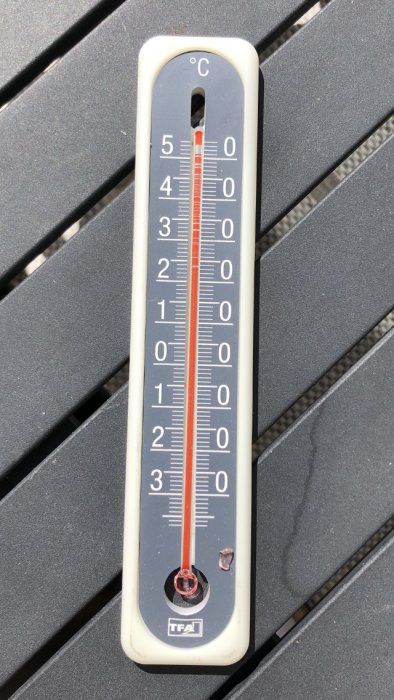 Analog termometer som visar temperatur på en grå yta.