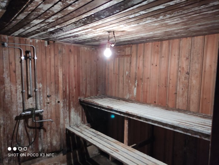 En fuktig källare med mögel på träbjälkar och panelväggar, i behov av reparation.