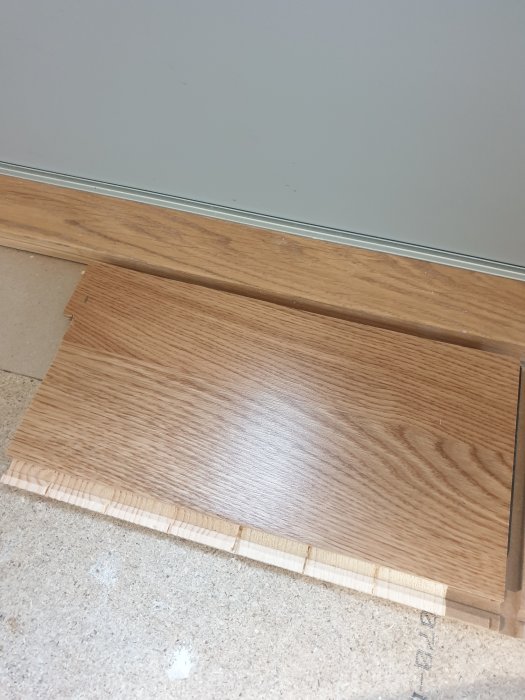 Ytterdörrtröskel i linje med parkettgolv som slutar utan list, risk för snubbel.