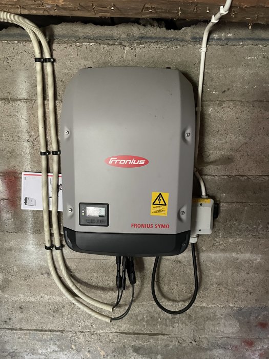 Fronius Symo solinverter monterad på en betongvägg i ett fritidshus.