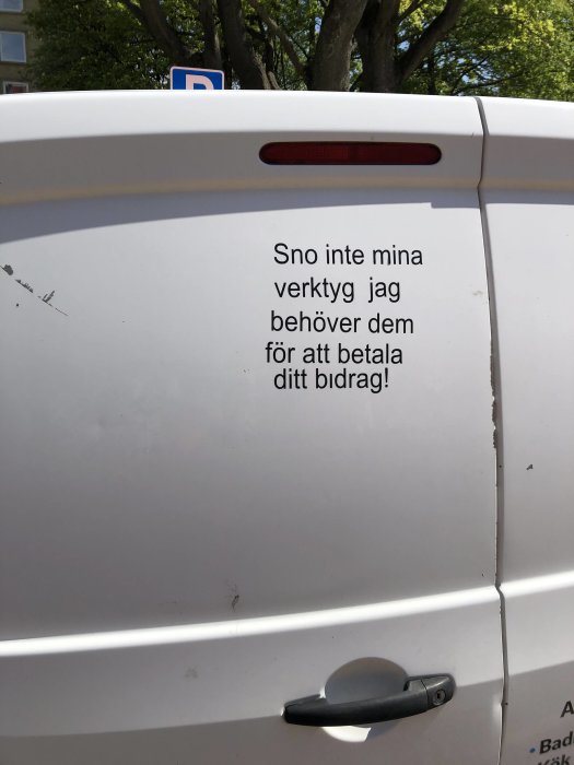 Bakdörr till en vit skåpbil med texten "Sno inte mina verktyg jag behöver dem för att betala ditt bidrag".