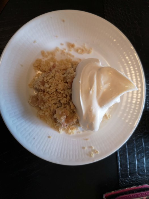 En portion rabarberpaj med vaniljsås på en vit tallrik, presenterad som sommarens första dessert.