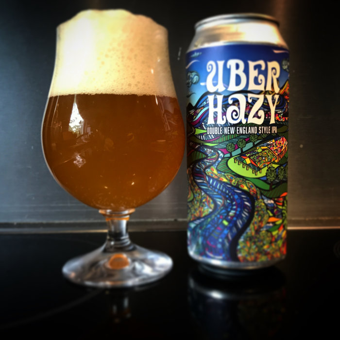 En välskummad öl bredvid en burk med texten "Über Hazy Double New England Style IPA".