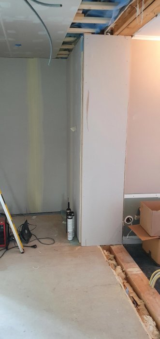 Renovering pågår med osammanhängande gipsskivor, spackel och verktyg på golvet i hallen där skjutdörrar ska installeras.