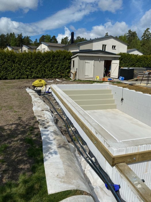 Bärlina installerad runt en pool med nybesågade reglar mot en husbakgrund på en solig dag.