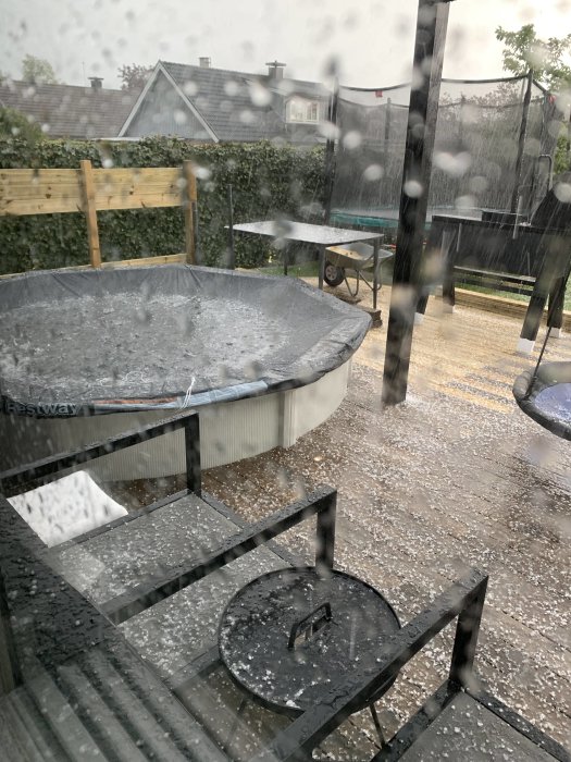 Utespa och utemöbler täckt med ett lager hagel under en kraftig hagelskur.