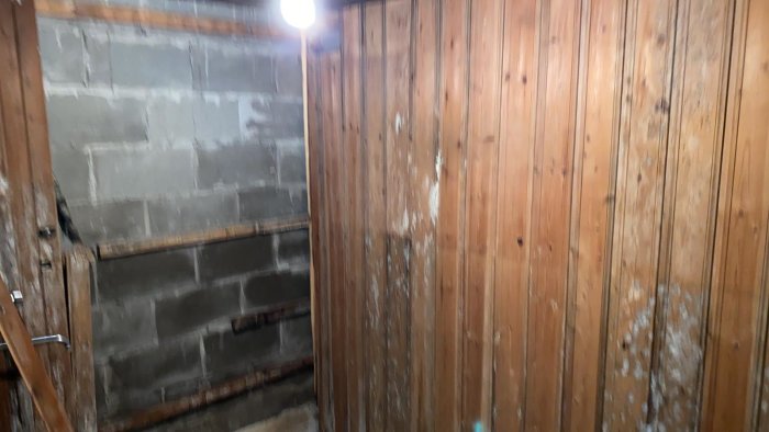 Delvis riven bastuinredning med nakna betongväggar och träpanel.