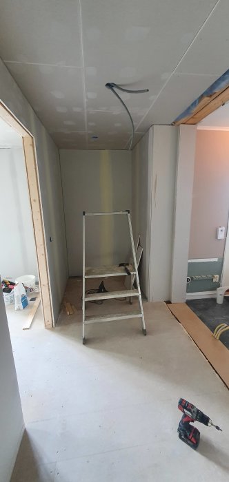 Renovering av hall med gipsskivor, spackel, stege och en skruvdragare på golvet.