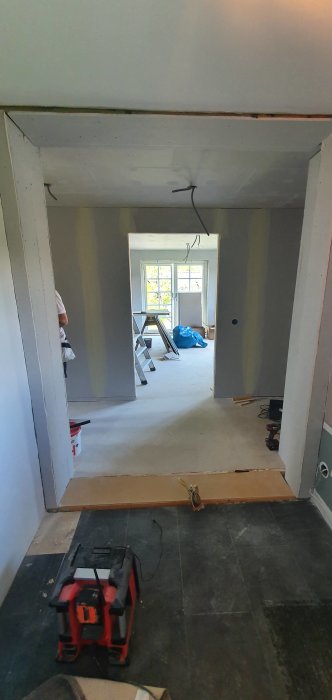 Renovering av en hall under arbete med gipsskivor, stegar och verktyg synliga.