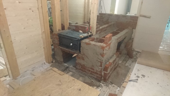 Konstruktion av en köksspis och bakugn i tegel under byggnation i ett rum.