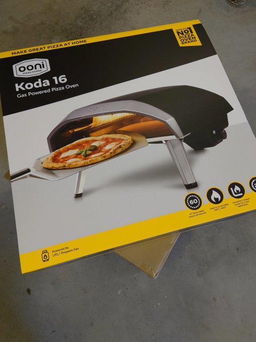 Förpackning av en Ooni Koda 16 gasdriven pizzaugn med bild av ugn och pizza.