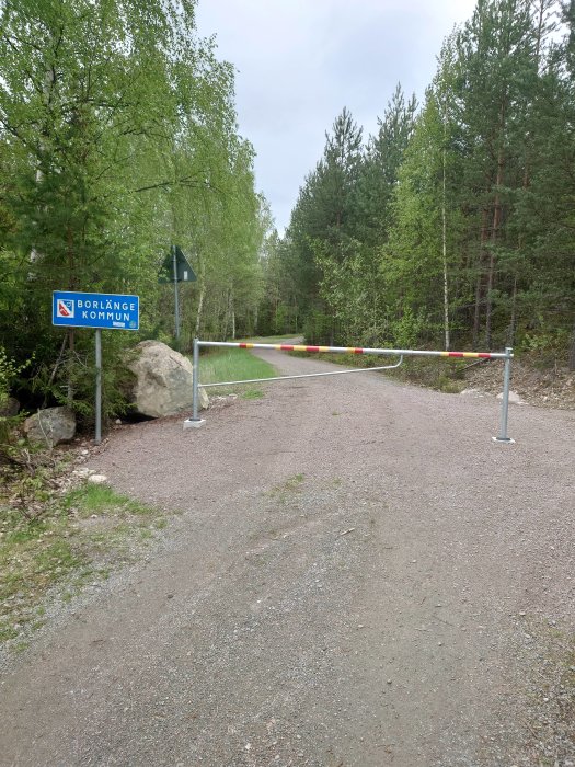 Spärrad grusväg vid skylten "Borlänge kommun" med skog i bakgrunden.