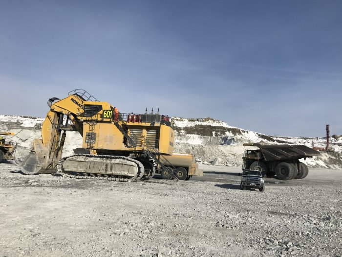 Grävmaskin och dumper i grustag, grävmaskinen märkt 601, dumpern betydligt större än en pickup.