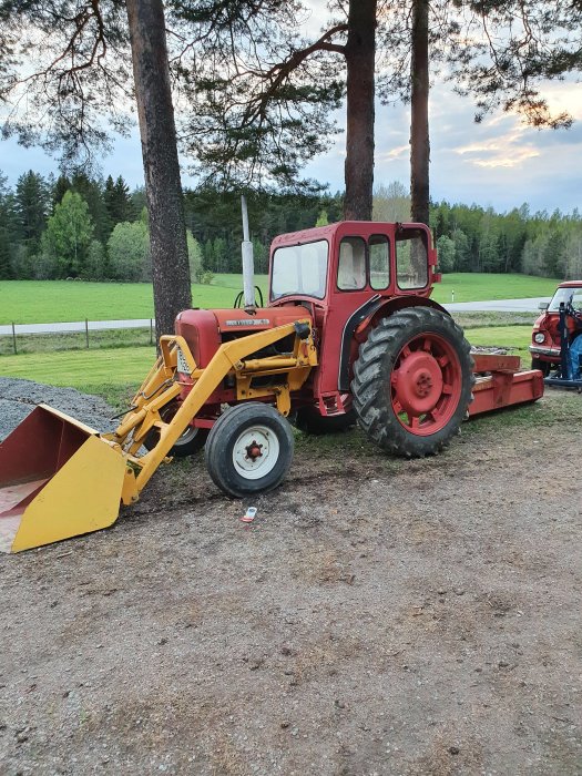 Röd Nuffield 10/60 traktor från 1965 med gul frontlastare och röd plogblad.