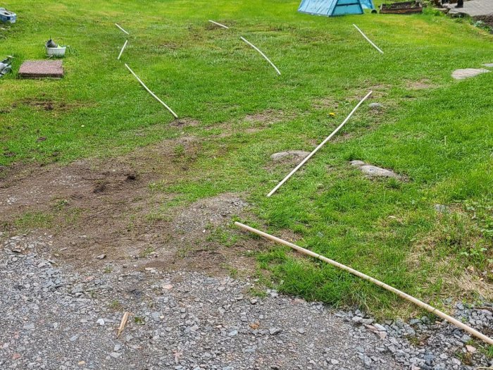 Vattensjuk gräsmatta markerad för dränering med vita linjer som visar förslag på rördragning.